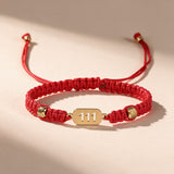 111 Angel Number Bracelet full view: braided red string, gold-tone 111 charm plate and adjustable slide knot