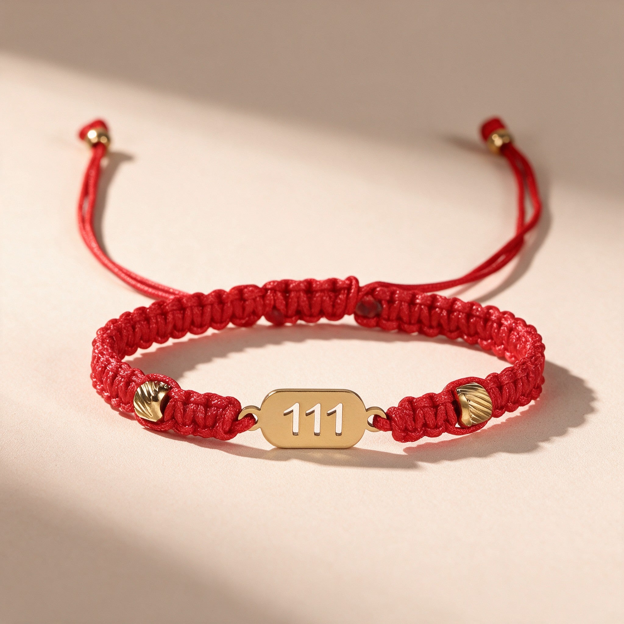 111 Angel Number Bracelet full view: braided red string, gold-tone 111 charm plate and adjustable slide knot
