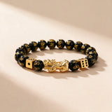 Black obsidian Pixiu bracelet full view: gold-tone Pixiu, two gold dice and mantra-carved 10mm obsidian beads