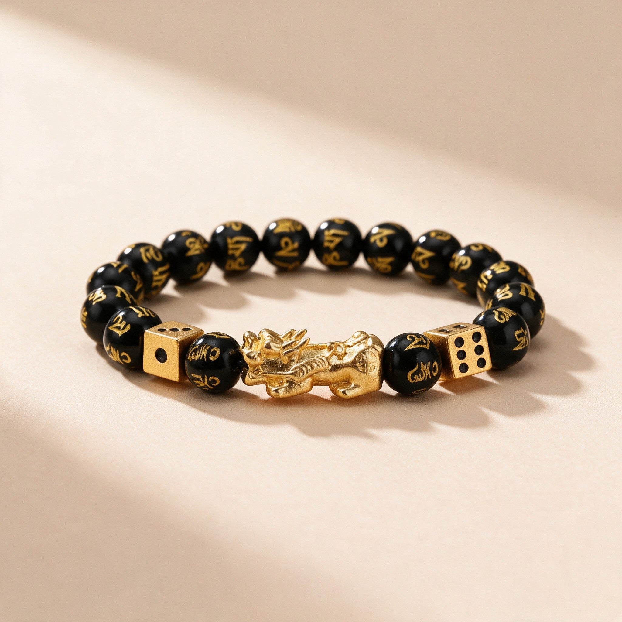 Black obsidian Pixiu bracelet full view: gold-tone Pixiu, two gold dice and mantra-carved 10mm obsidian beads
