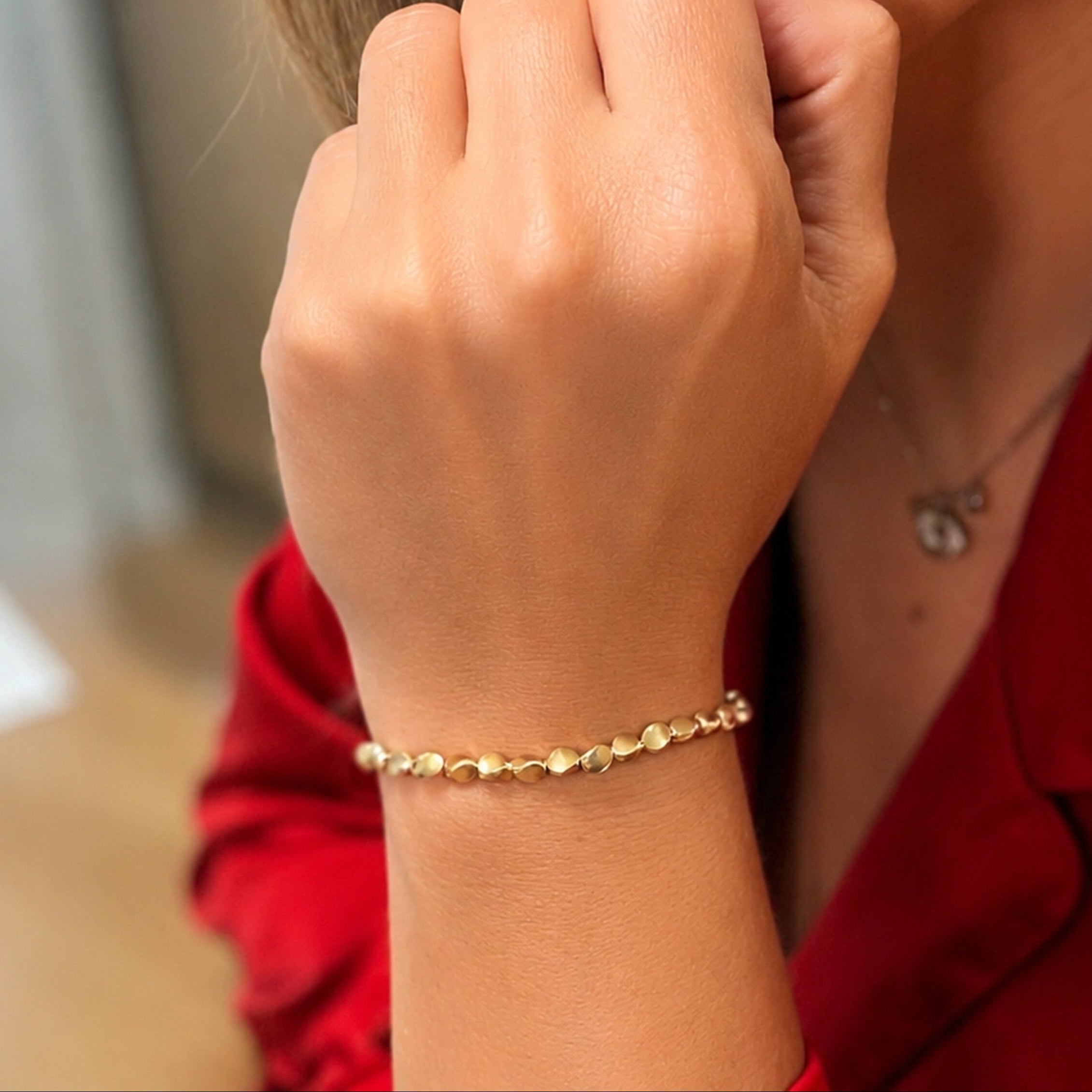 Close-up of a woman wearing a gold bracelet with a blurred background