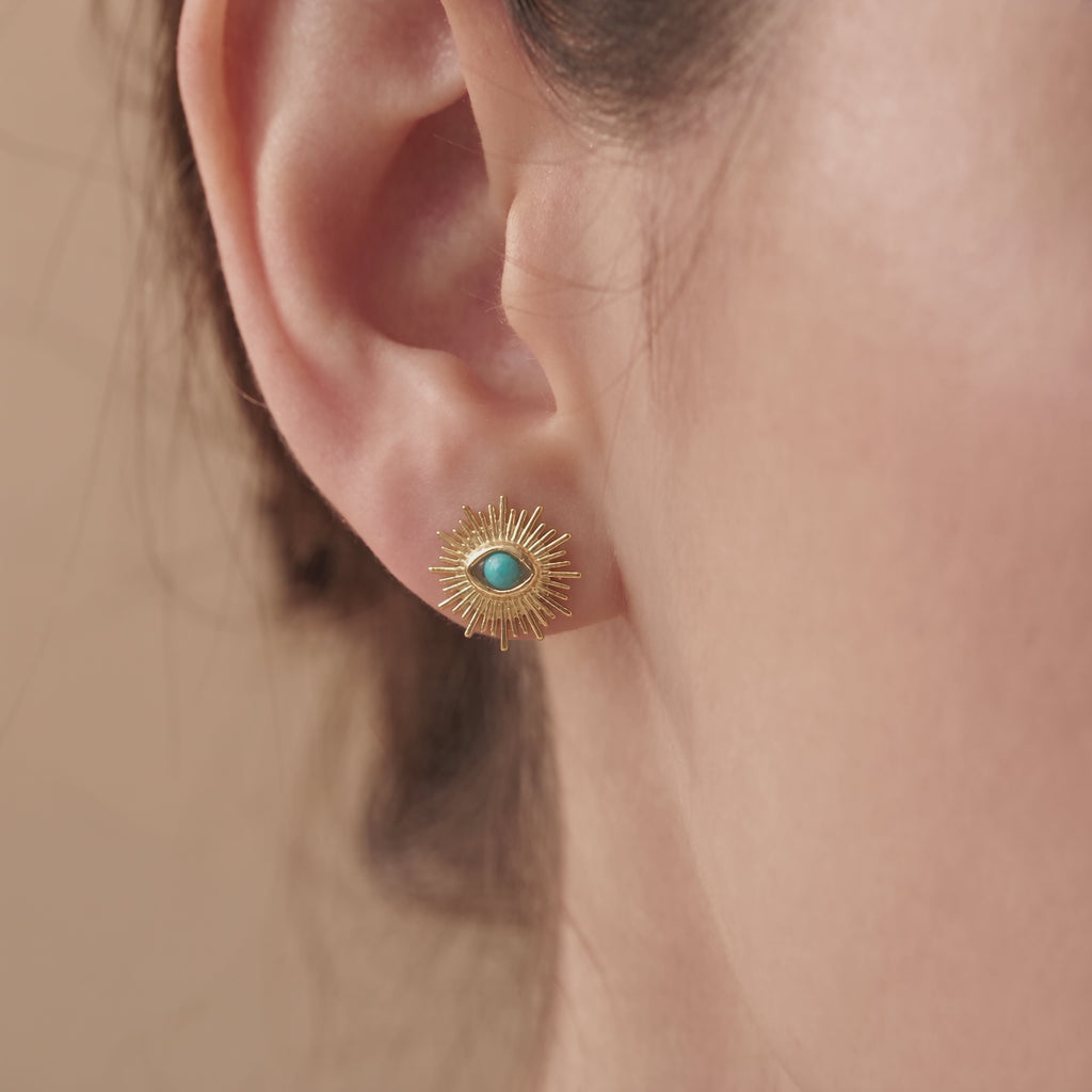 A video of a woman wearing the sunrays evil eye earrings